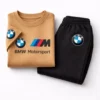 Toddler boy modeling a camel-colored BMW Motorsport short-sleeve t-shirt and black jogger pants tracksuit.